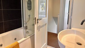 A modern bathroom with a glass-enclosed shower, a white bathtub, and a sink. - Charming 1-Bedroom House in Wonderful London with WiFi (London)