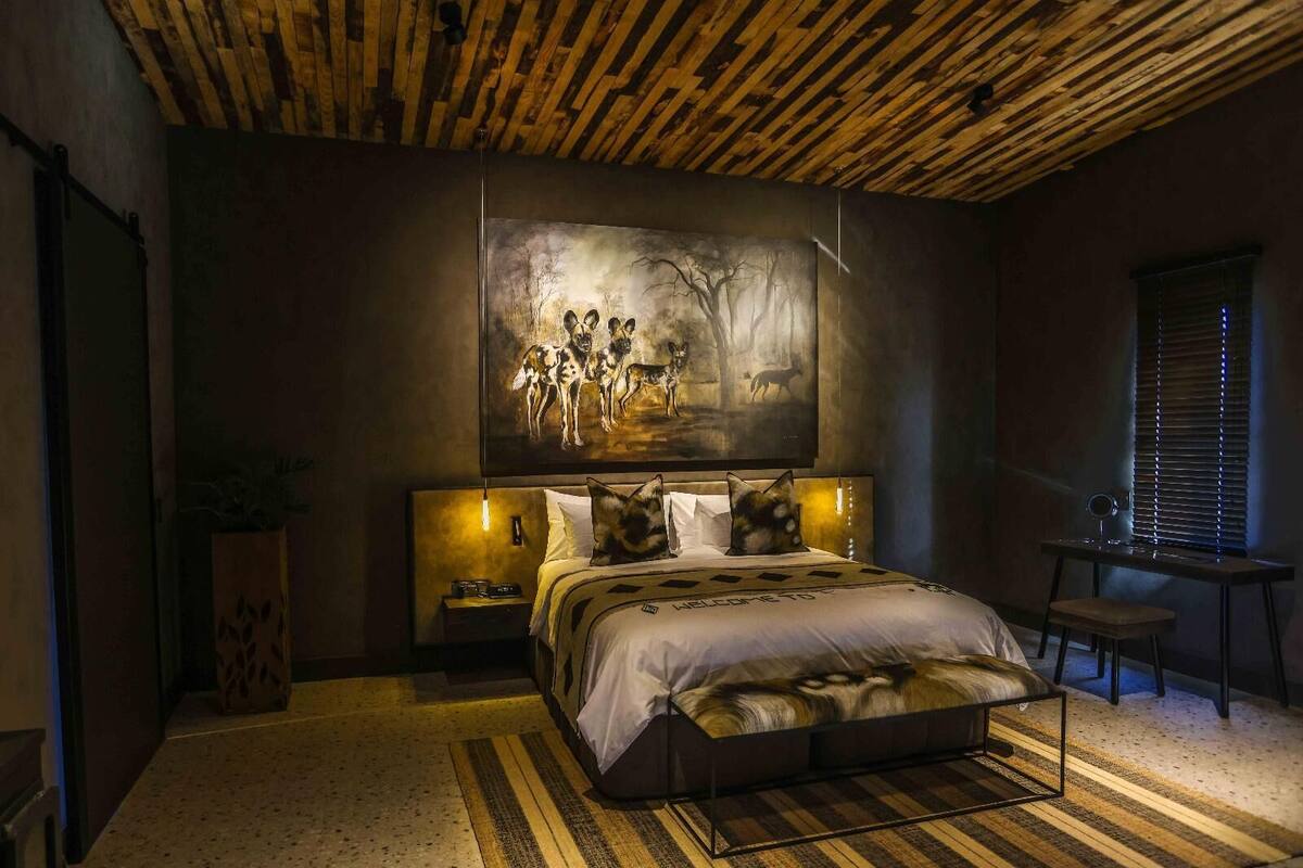 Un dormitorio con cama, mesita de noche, silla, escritorio y un cuadro en la pared.