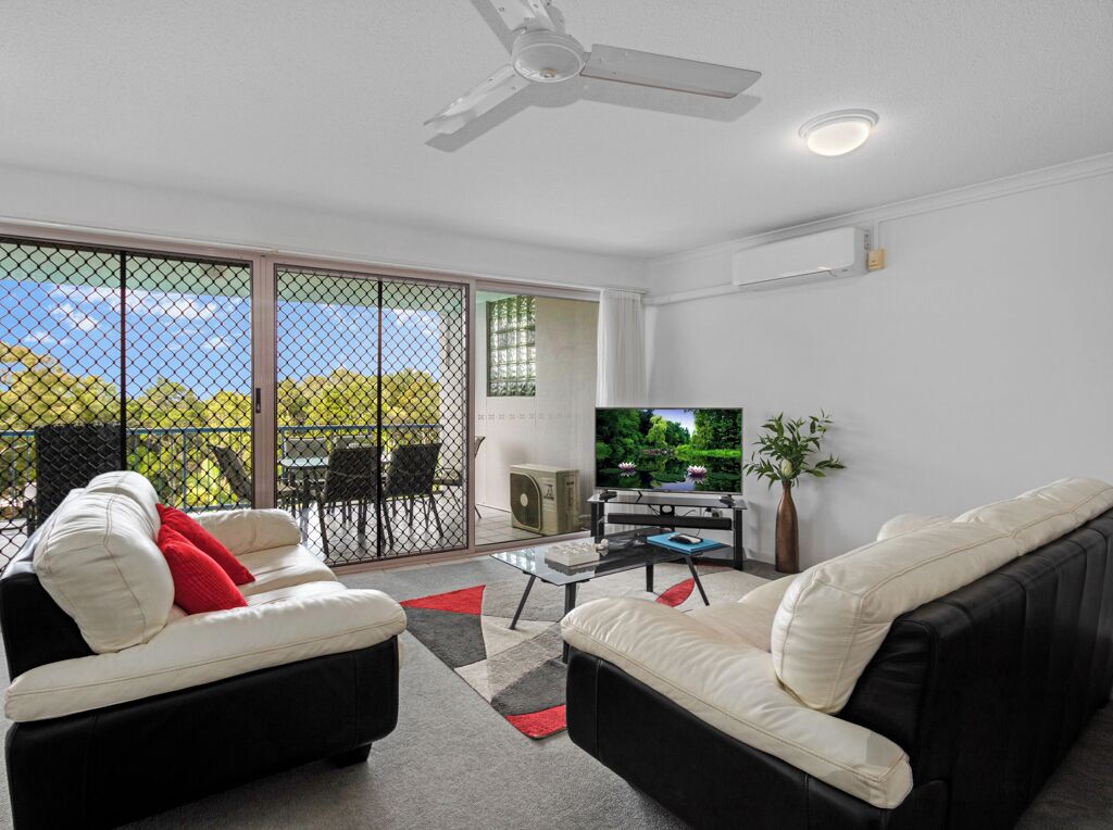 A living room with a sofa, a coffee table, a TV, and a ceiling fan.