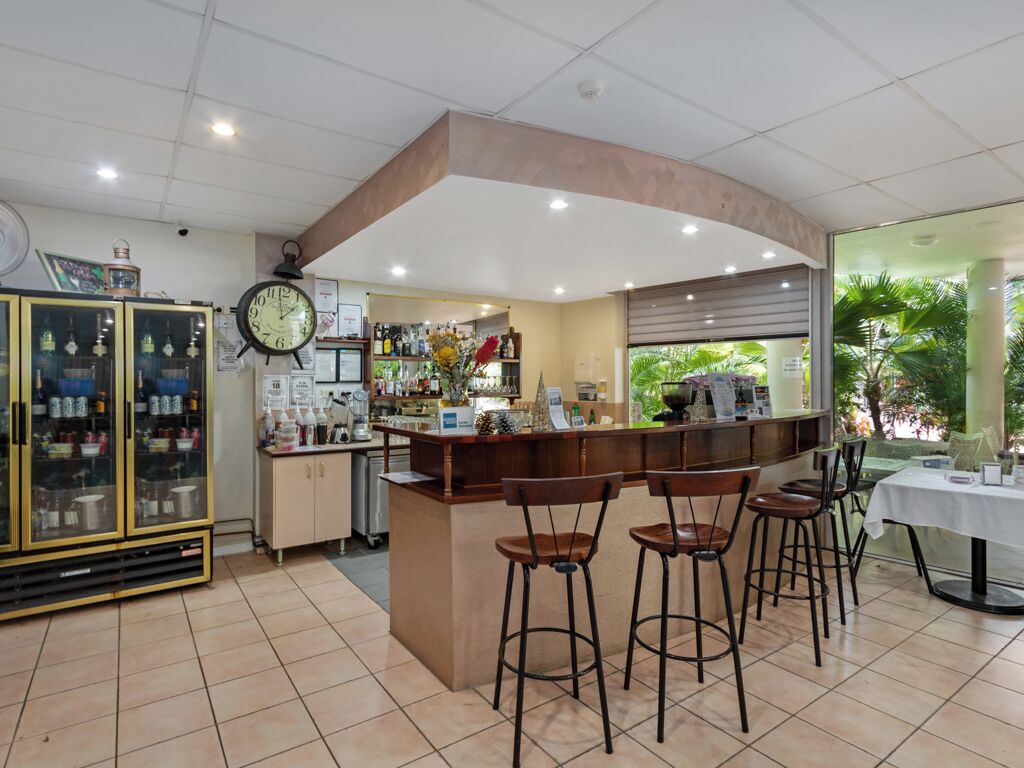A bar area with stools, a clock, and a counter with various items.