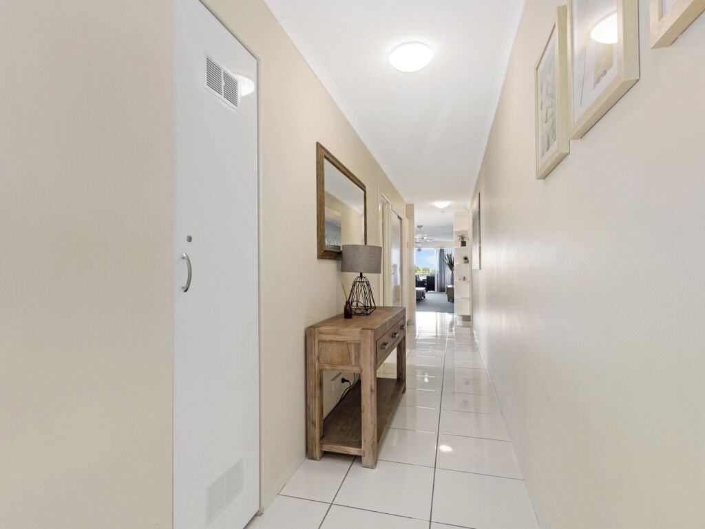 A hallway with a wooden console table, a mirror, and framed pictures on the walls.