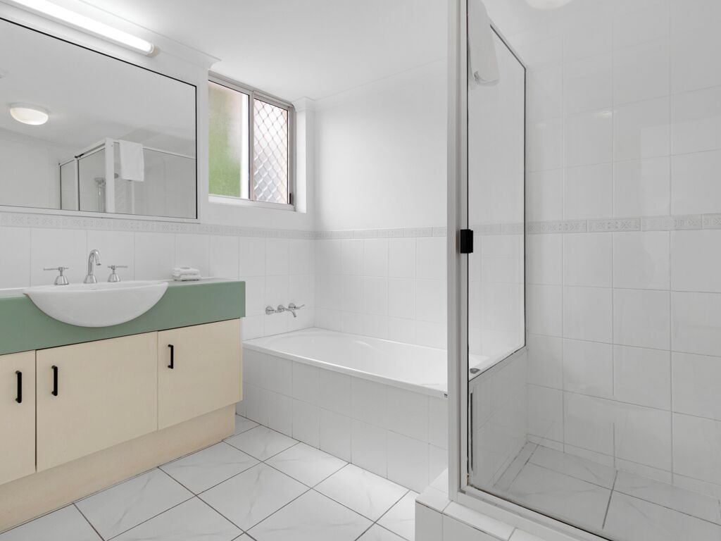 Un baño moderno con un espejo grande, un lavabo, una bañera y una zona de ducha con mampara de cristal.