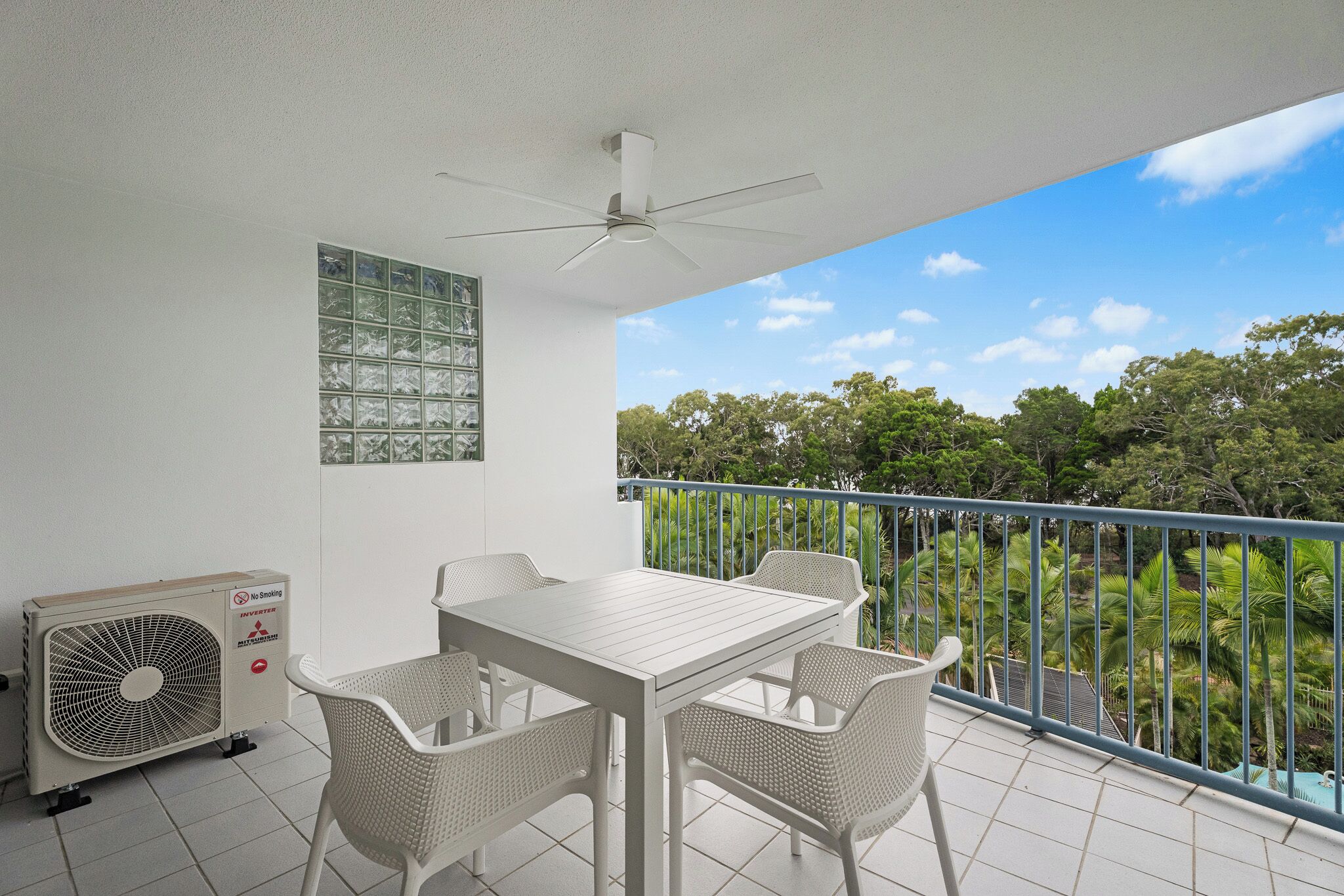 A balcony with a table and chairs, a ceiling fan, and an air conditioning unit.