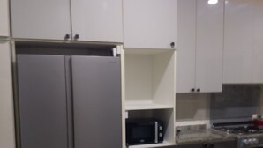 A kitchen with two stainless steel refrigerators, a microwave, and a stove. - Favour home (Abuja)