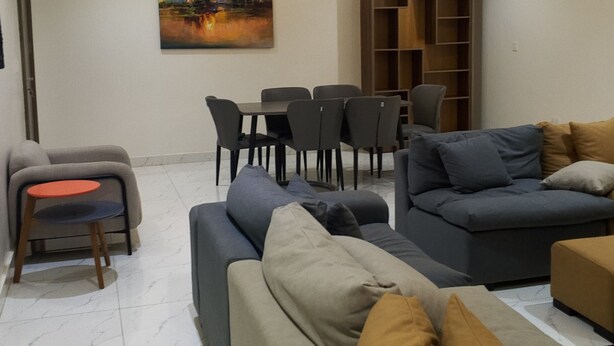 A modern living room with a sofa set, a dining table with chairs, and a painting on the wall. - Favour home (Abuja)