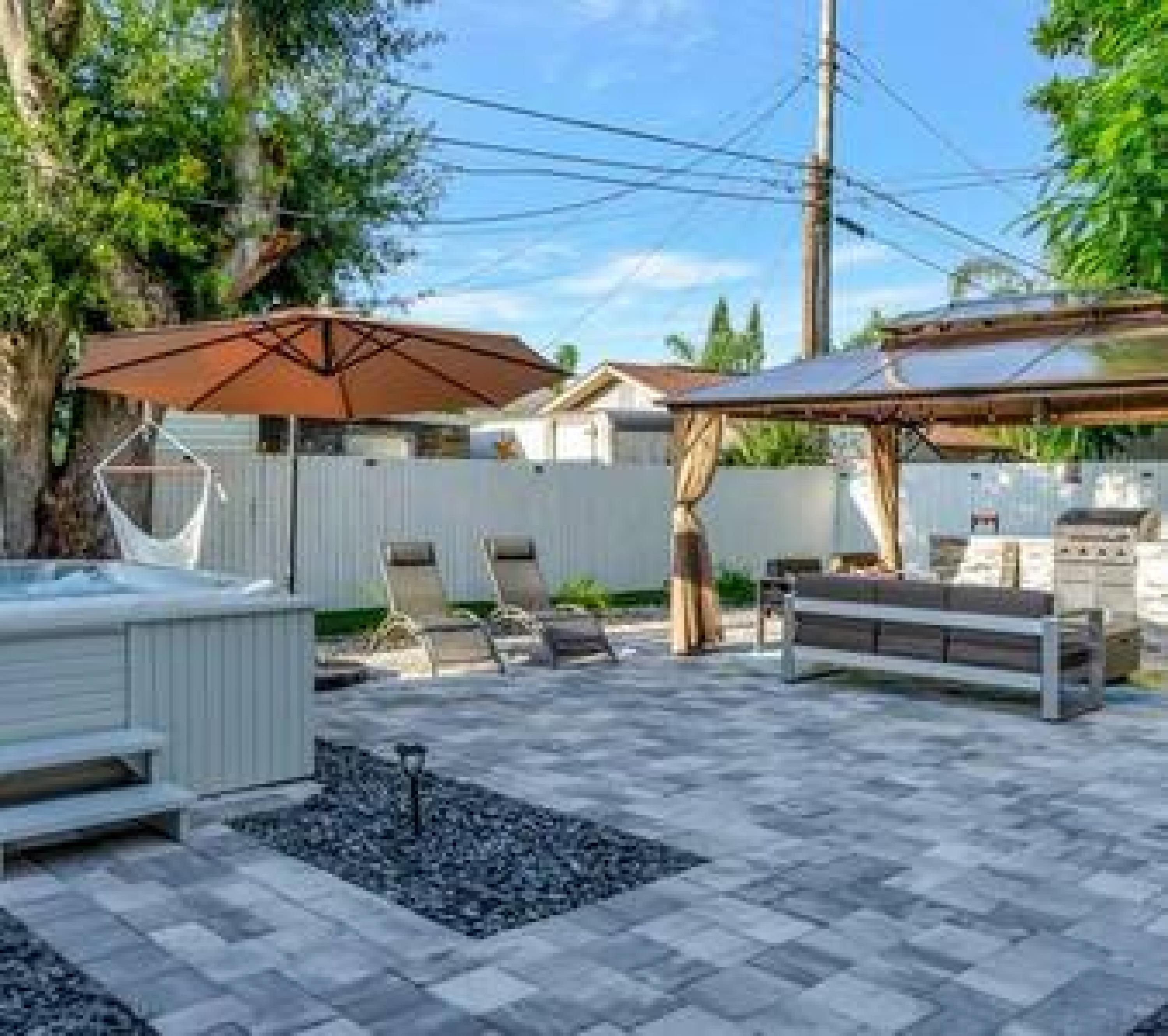 A backyard with a hot tub, patio furniture, and a pergola.