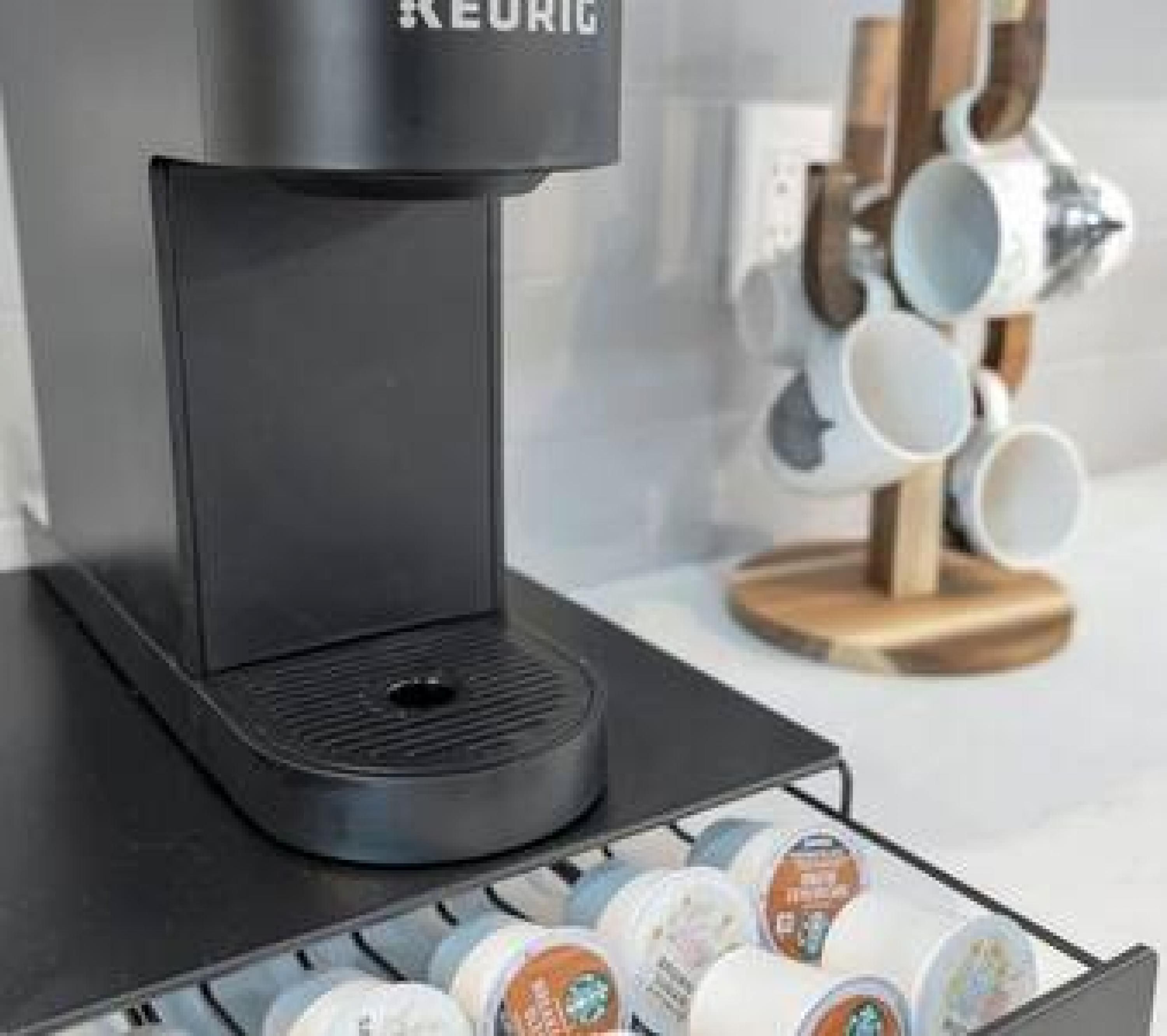 A black coffee machine with a drip tray and a coffee pod holder below it.