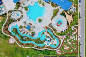 An aerial view of a resort with multiple swimming pools, landscaped areas, and a central circular water feature. - Ohana Gathering House (Davenport)