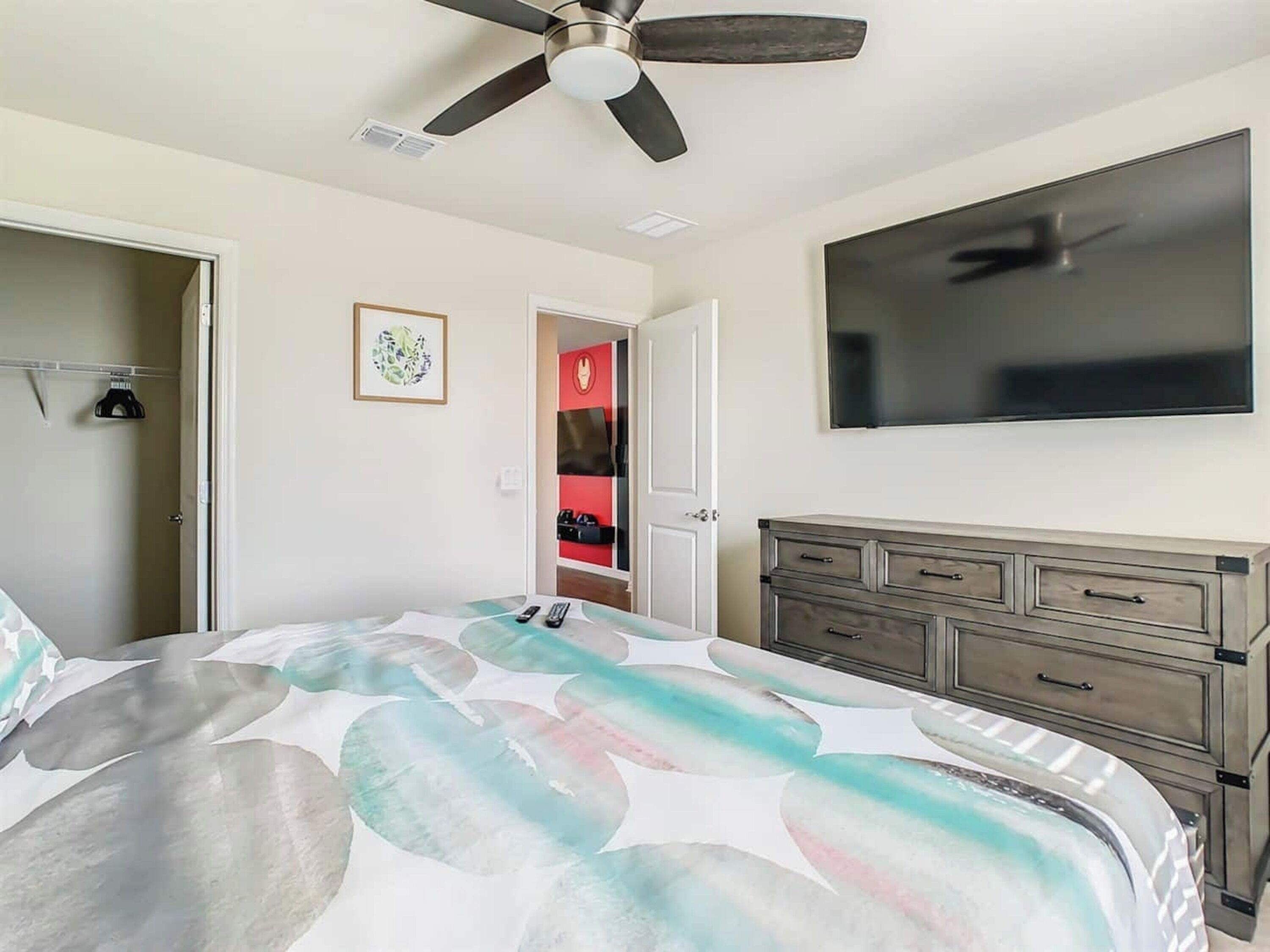 Une chambre à coucher comprenant un lit, un ventilateur de plafond, une télévision, une commode et un placard.