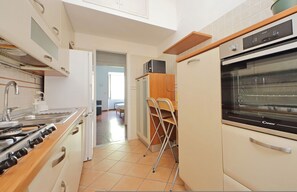 Une cuisine équipée d’une cuisinière, d’un four et d’une chaise.