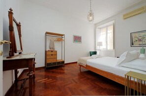 Une chambre à coucher avec un lit en bois, une commode en bois, un miroir, une armoire et un lustre.