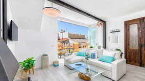 A modern living room with a glass coffee table, white sofas, and a view of the street outside. - Solaga - Noemi Centro (Málaga)
