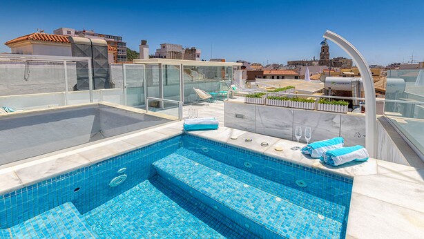 A rooftop swimming pool with glass railings, lounge chairs, and a view of the cityscape. - Solaga - Noemi Centro (Málaga)