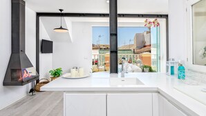 A modern kitchen with a large island, a built-in stove, and a view of the cityscape. - Solaga - Noemi Centro (Málaga)