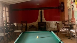 A pool table in a room with red walls, a fireplace, and wooden furniture.