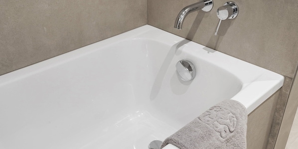 Una bañera blanca con un solo grifo y una toalla al lado.