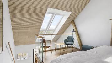 Quarto tipo loft moderno com teto inclinado, claraboia e cama.