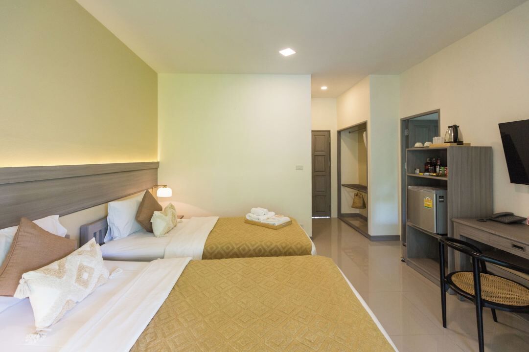 A hotel room with two beds, a desk with a chair, a television, and a minibar.