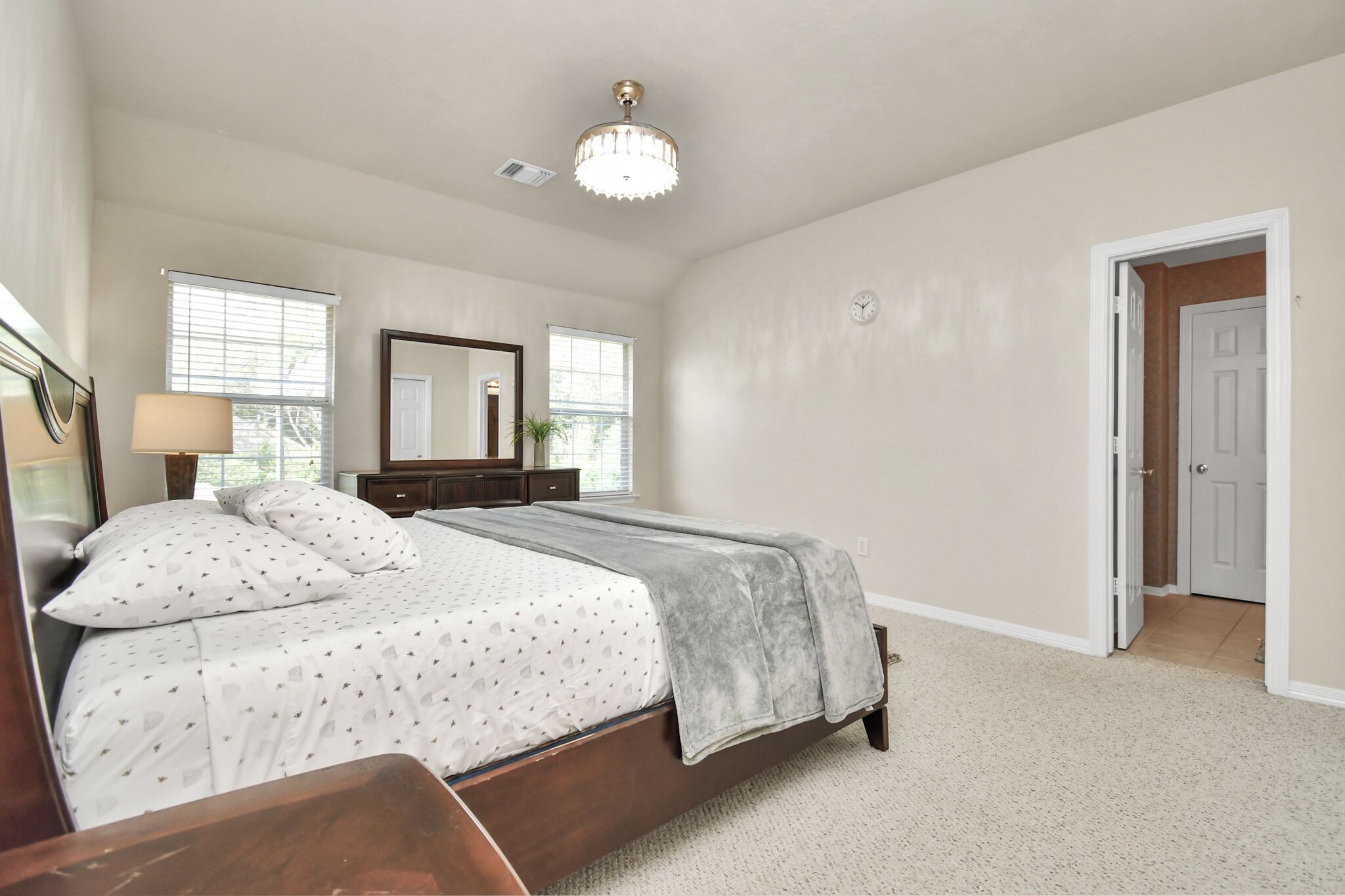 A bedroom with a bed, a dresser, a mirror, and a door.
