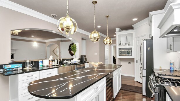 A modern kitchen with a large island, stainless steel appliances, and pendant lighting. - REIGN Mini-mansion (Houston)