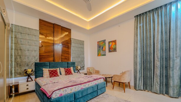 A modern bedroom with a large bed, a bedside table, a chair, and a small table. - VIBE 2.0 (Jaipur)