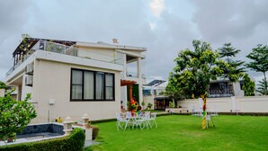 A modern two-story house with a balcony, a well-maintained lawn, and outdoor seating. - VIBE 2.0 (Jaipur)