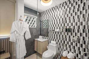 Enjoy a refreshing bathroom experience with a geometric-patterned tile backsplash, sleek toilet, and spacious vanity.