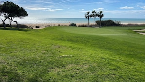 A golf course with a beach view, palm trees, and a flag. - Seaview Apartment Estrela da Luz, Praia da Luz (Lagos)