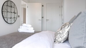 Un dormitorio con una cama, un espejo grande y una pila de toallas.