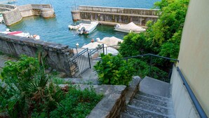 Escadaria descendo para um areal com barcos atracados.