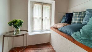 A cozy corner with a window, a small table with a vase, and a bed with pillows. - Beach Lake Bellagio by Wonderful Italy (Bellagio)