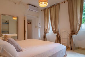 Un dormitorio con cama, espejo, cortinas y ventana.