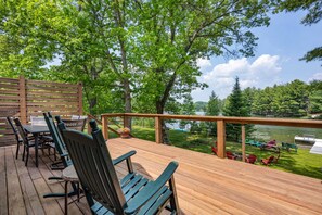 A wooden deck with outdoor seating and a view of a lake.