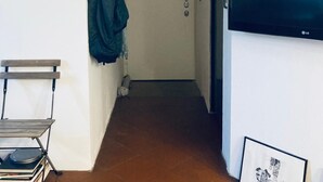 A narrow hallway with a coat rack, a door, and a television mounted on the wall.