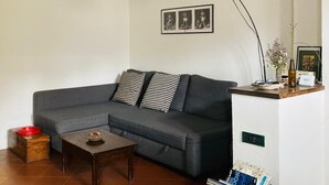 A living room with a grey sofa, a wooden coffee table, a wicker lamp, and a framed photo on the wall.