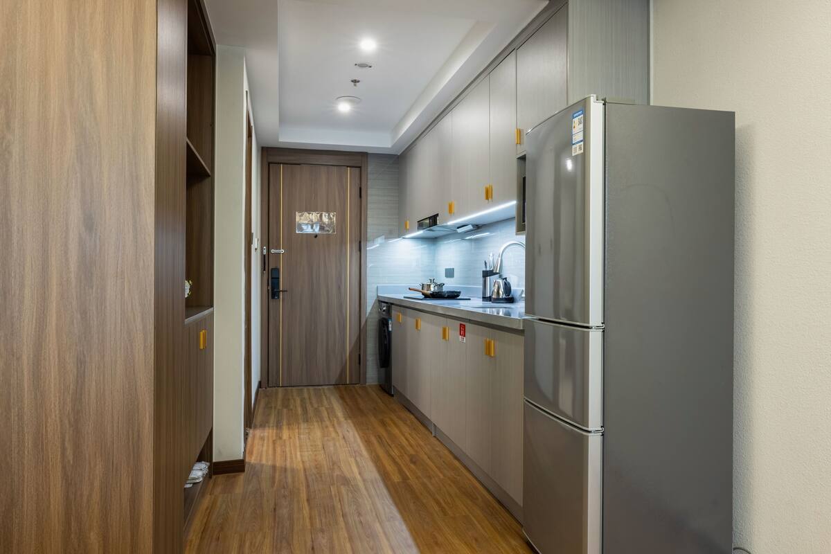 A modern kitchen with wooden cabinets, a stainless steel refrigerator, and a built-in stove.