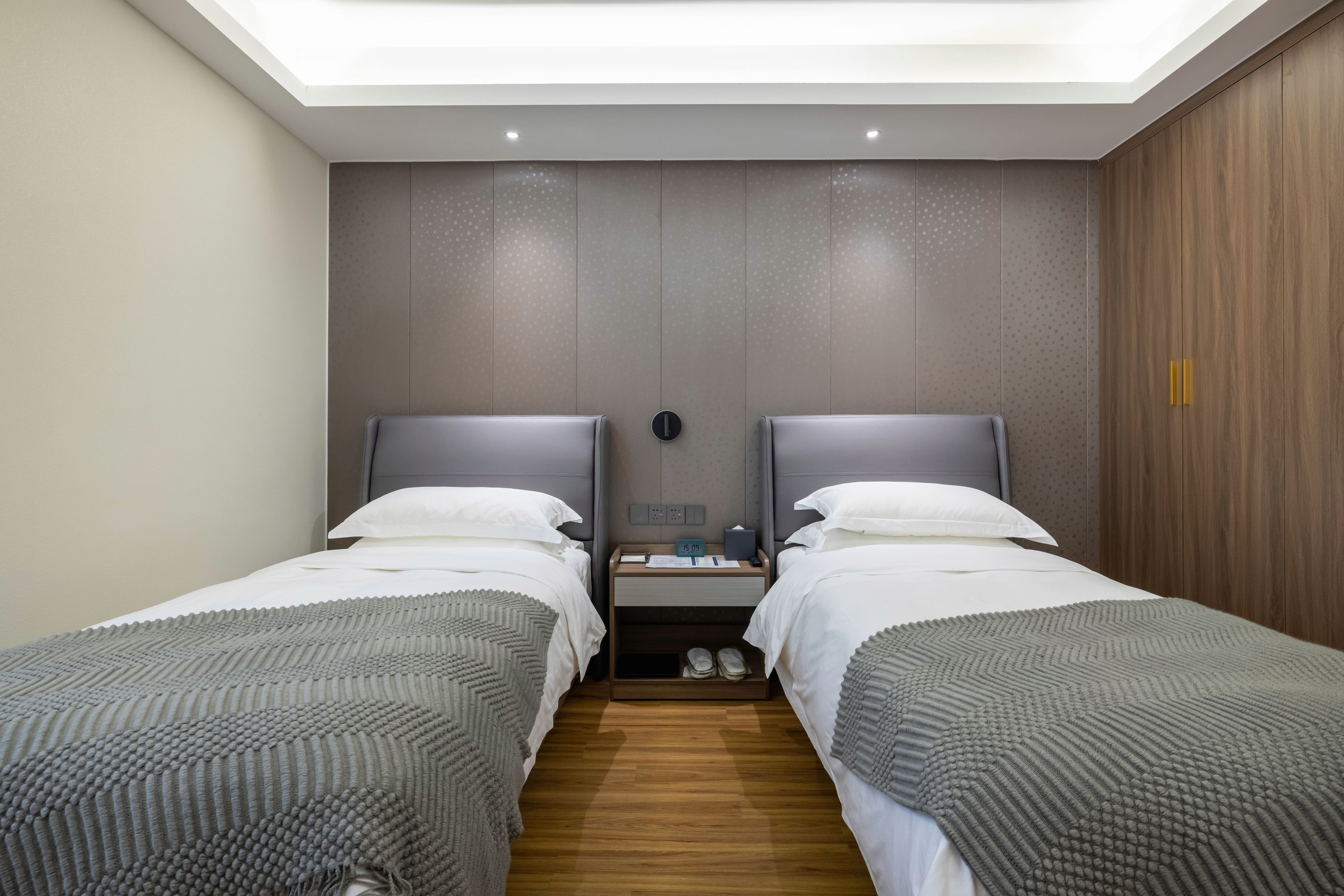 Habitación de hotel con dos camas individuales, una mesita de noche con lámpara y un tragaluz.