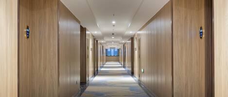 A long, narrow hallway with wooden paneling on the walls and a patterned carpet.