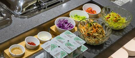 A buffet with various food items and condiments.