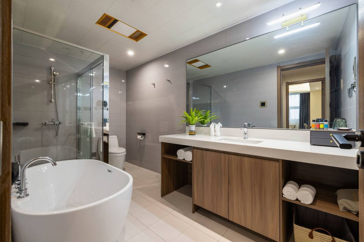 A modern bathroom with a freestanding bathtub, a large mirror, and a vanity with a sink and countertop.