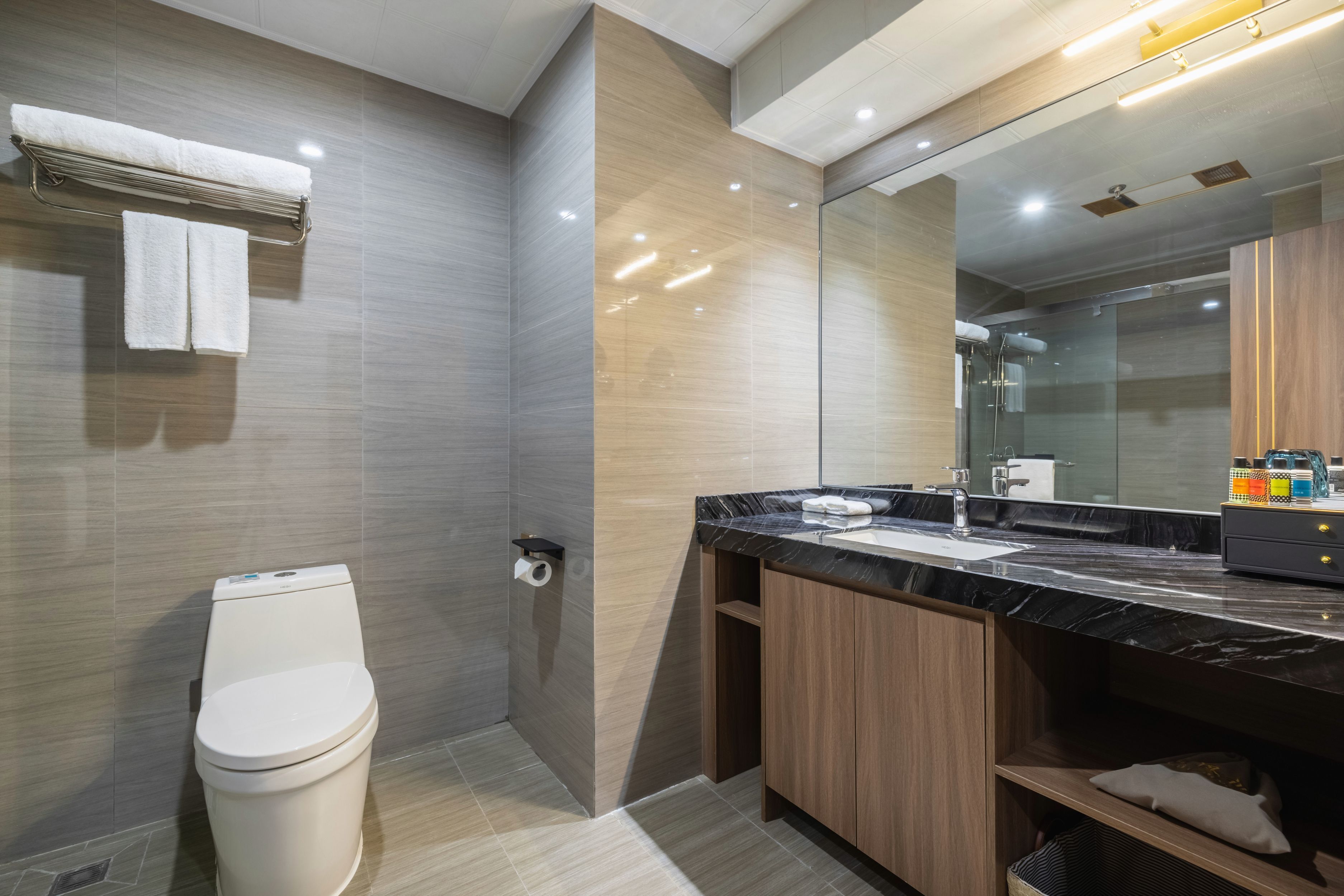 A modern bathroom with a toilet, sink, and mirror.