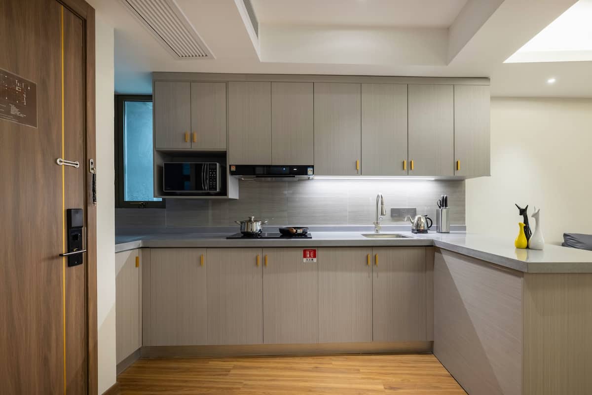 A modern kitchen with grey cabinets, a microwave, a stove, and a sink.