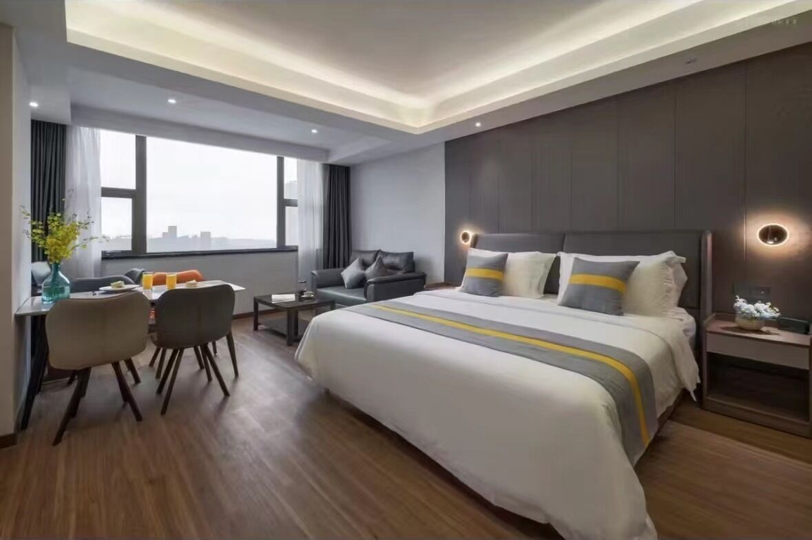 Ein modernes Hotelzimmer mit einem großen Bett, einem Schreibtisch mit Stühlen, einem kleinen Tisch und einem Nachttisch.