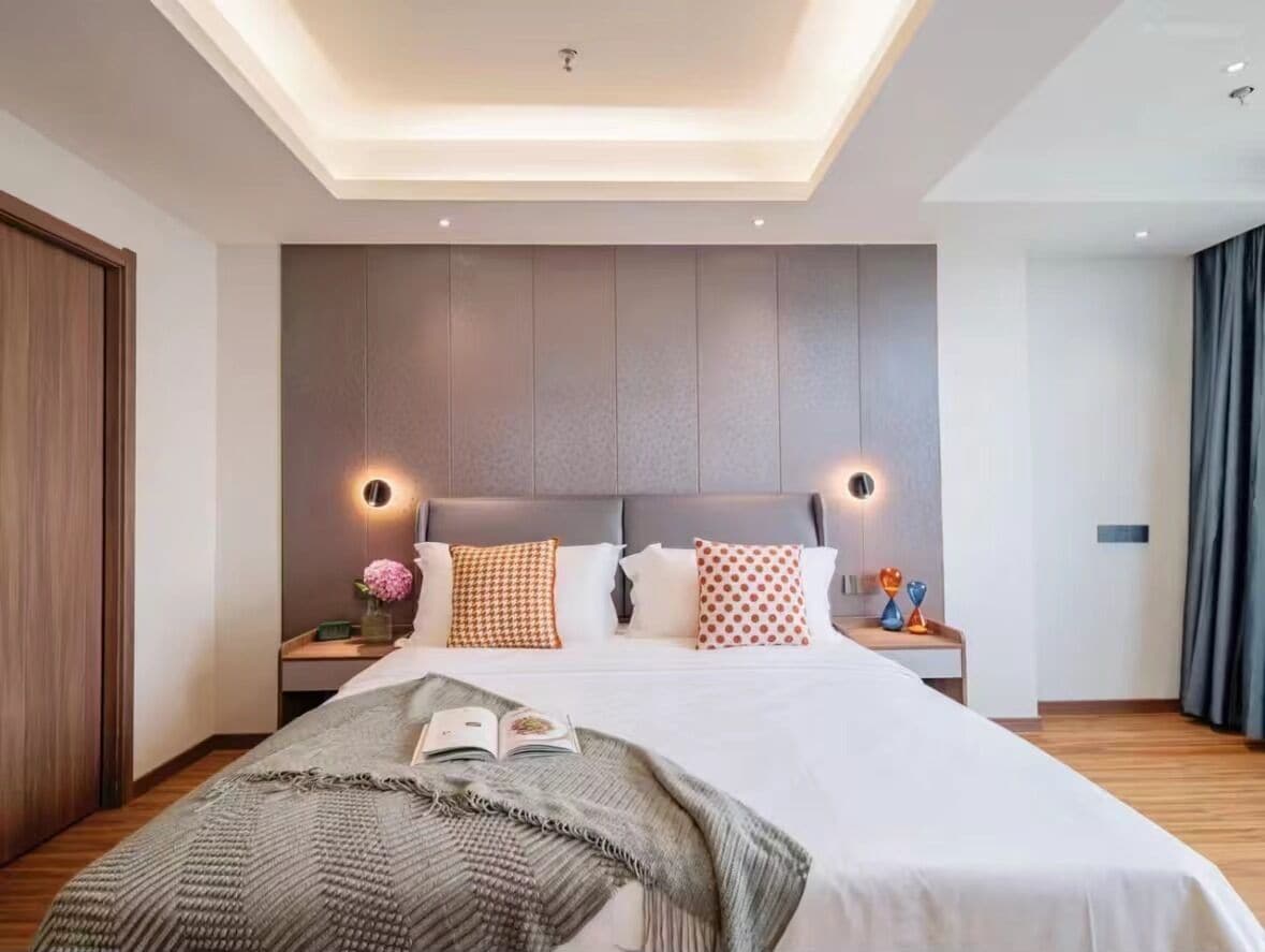 A modern bedroom with a large bed, bedside tables, and a ceiling light fixture.