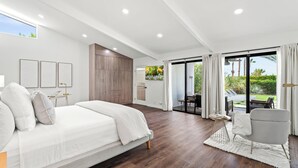 A modern bedroom with a large bed, a seating area, and a view of the outdoors.