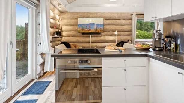 Een moderne keuken met een groot fornuis, witte kasten en een houten wand.