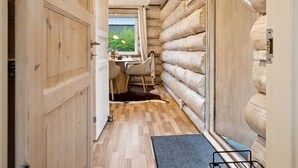 Het interieur van een blokhut met een eethoek, houten wanden en uitzicht op groen.