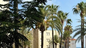 Um resort com piscina, palmeiras e um edifício com várias janelas.