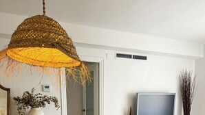Uma sala de jantar com mesa de madeira, cadeiras e luminária pendente.