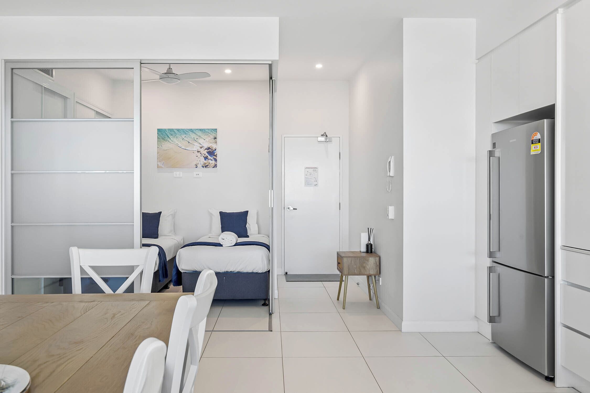 Una habitación de hotel moderna con cama, una mesita pequeña y una kitchenette.